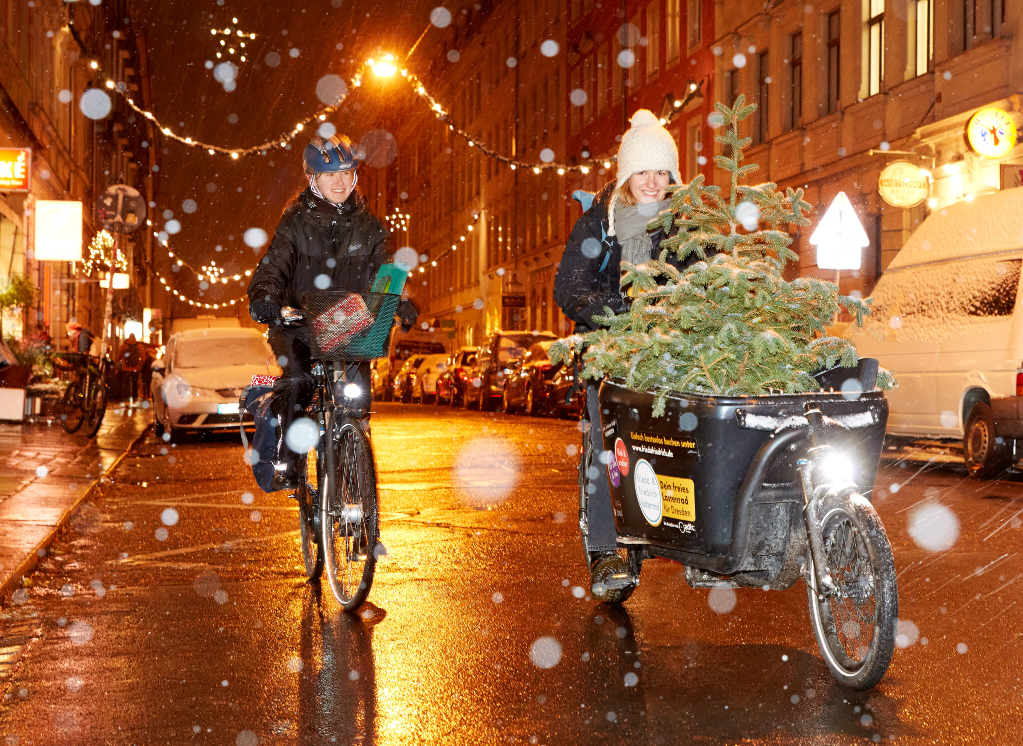 Zwei Frauen mit Fahrrad, Lastenrad und Weihnachtsbaum